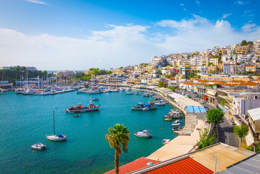 Ein Blick auf eine griechische Küste mit Wasser, Booten und einer Stadt.